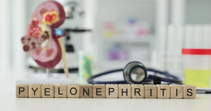Word Pyelonephritis made of wooden cubes against model of human kidney and urological equipment. Diagnosis of dangerous kidney infection