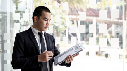 Handsome job applicant is standing in the office and holding portfolio waiting for job interview.