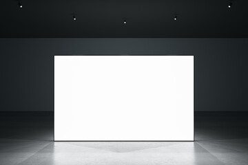 Front view of blank white glowing digital screen in dark hall interior with concrete floor and black wall. Presentation concept. Mockup, closeup, 3D Rendering