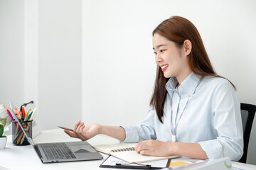 Beautiful young asia businesswoman’s sitting in the office room and using computer to plan about marketing investment for her business.