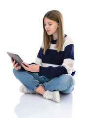 Obraz premium Full length portrait of pretty girl sitting on floor working on laptop pc computer isolated on white background. Fourteen year old teenager in striped sweater reading and posing in studio.
