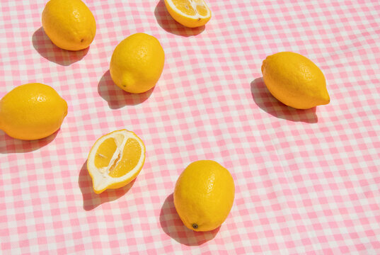 Summer creative layout with lemons on pastel pink plaid  background. 80s or 90s retro aesthetic idea. Minimal summer fruit idea.