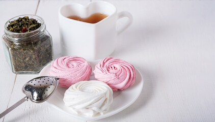 Pink and white marshmallows with breakfast tea, a place for text and design.