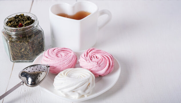Pink and white marshmallows with breakfast tea, a place for text and design.