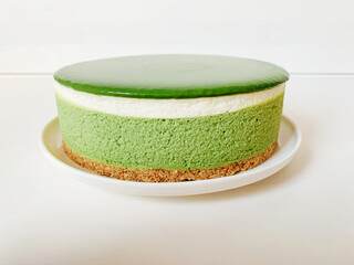 Layered matcha cheesecake on white background. Gluten free no bake dessert. Healthy sweet food.