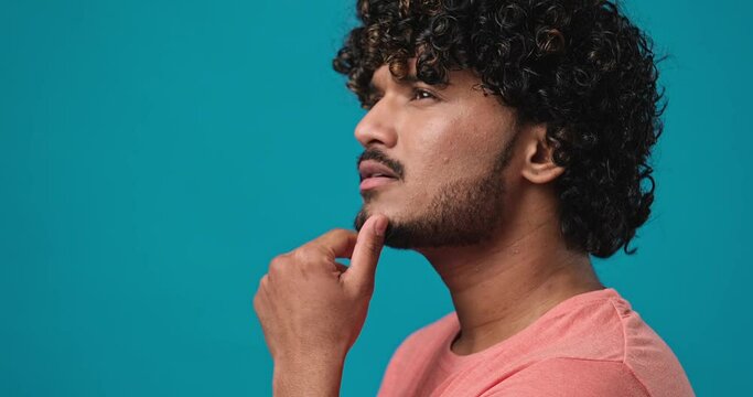 Serious pensive thinkful indian man standing isolated over blue studio background