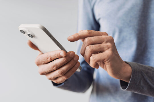 Closeup of adult male hand using mobile phone, Young man texting on smartphone over grey background.