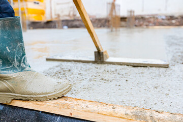 Construction worker, mason is leveling fresh concrete using handmade tool
