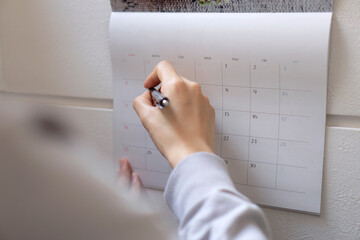 The woman writing schedule on calendar.  カレンダーに予定を書く女性