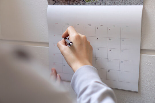 The woman writing schedule on calendar.  カレンダーに予定を書く女性
