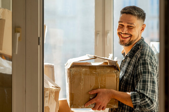 Smiling man holding cardboard box at home