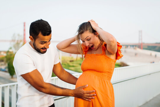 Man touching belly of surprised pregnant woman