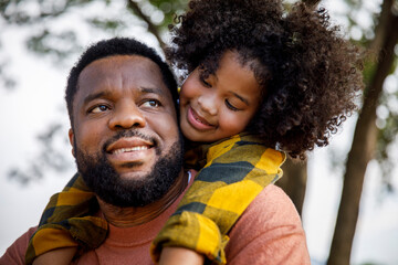 Contemplative man piggybacking daughter with curly hair