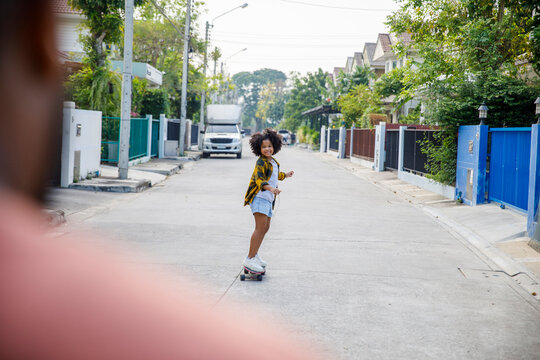 Smiling girl skateboarding on footpath