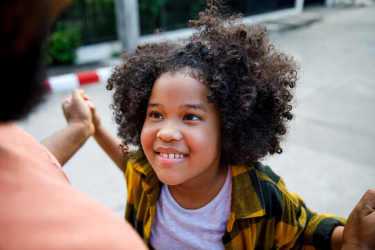 Smiling girl with curly hair looking at father