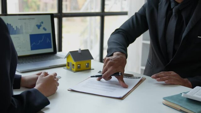 Asian real estate agent, and insurance salesman handing over a sample house to a client after signing the sale at the office.	