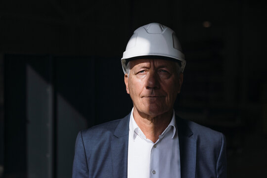 Businessman wearing blazer and hard hat in factory