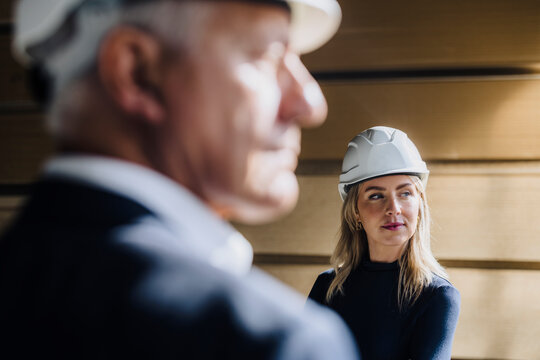 Businesswoman wearing hard hat with businessman in factory