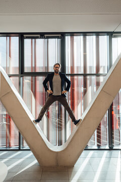 Businessman with arms akimbo standing on V-shaped column in building