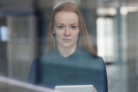 Redhead businesswoman at office seen through glass