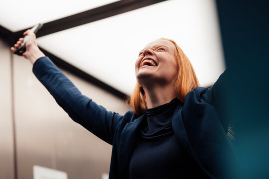 Happy businesswoman cheering in elevator