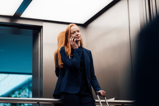 Businesswoman talking on smart phone in elevator