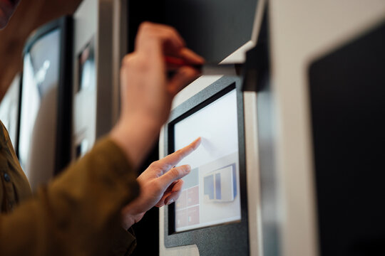 Woman touching screen of ATM machine
