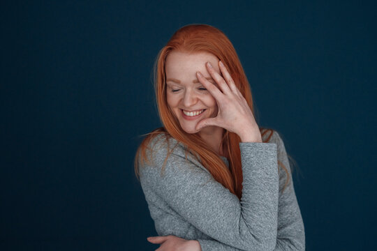 Happy woman touching face against blue background