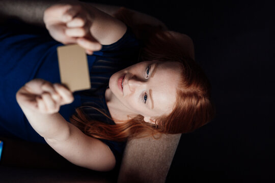 Young Woman Holding Credit Card Lying Down