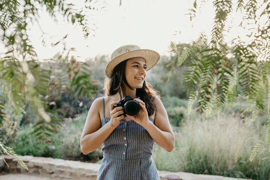 Smiling woman wearing hat holding camera