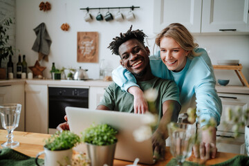 Young couple enjoying watching laptop in kitchen at home