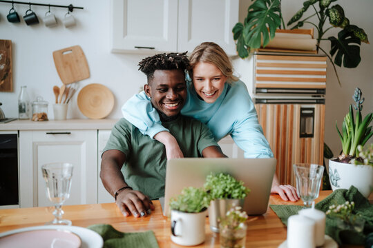 Smiling woman watching laptop with man at home