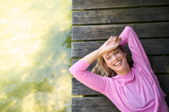 Happy mature woman lying down on boardwalk