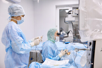 Nurse with surgeon performing eye surgery in operating room