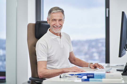 Portrait of smiling doctor sitting at desk in medical practice