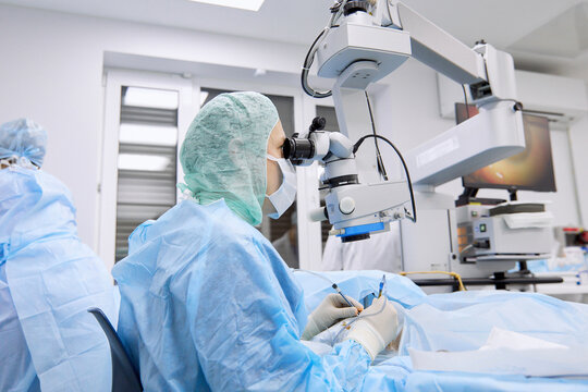 Surgeon performing eye surgery using microscope in operating room