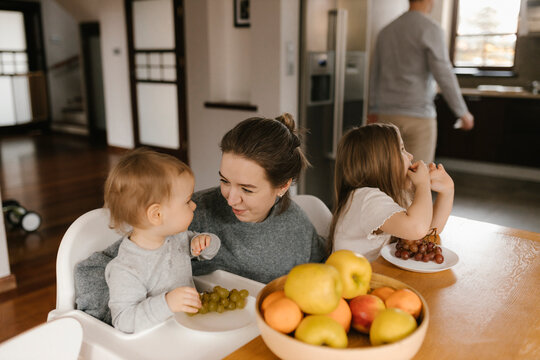 Mother with children eating fruit at dining table