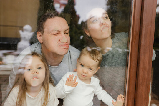 Family pressing noses against window in house