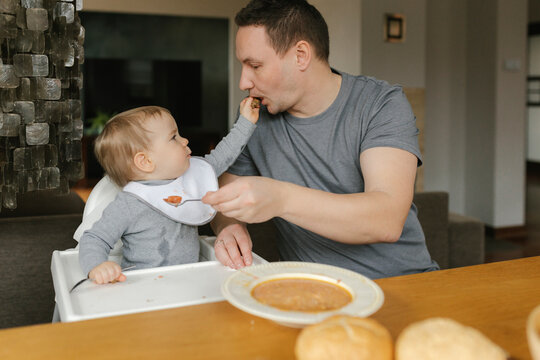 Father feeding soup to baby boy at dining table