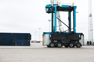 Shipping, cargo and logistics with straddle carrier for container, delivery and transportation at...