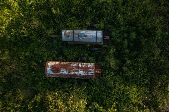 View over two old water bowsers in a field