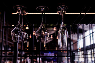 Lots of empty wine glasses hanging on the bar