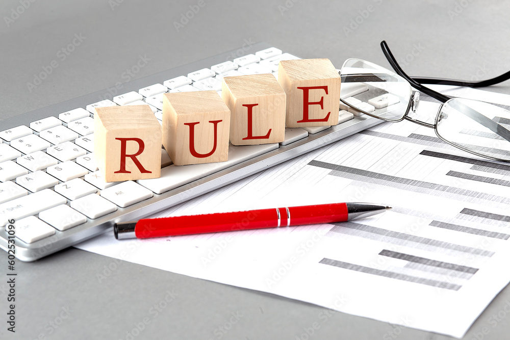 Poster rule written on a wooden cube on the keyboard with chart on grey background