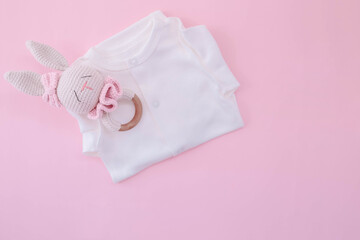 White bodysuit on a pink background. Waiting for the girl. Pregnancy. Clothes for newborns