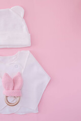 White suit on a pink background. Waiting for the girl. Pregnancy. Clothes for newborns