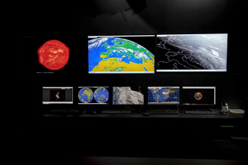 Monitors with space photos at the mission control station.