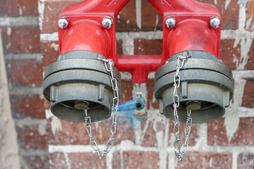 Hydrant with two taps for quick collection of water on a brick wall.