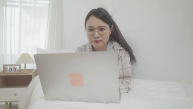 Asian freelance business woman using laptop 
 video call  freind in bed at home.