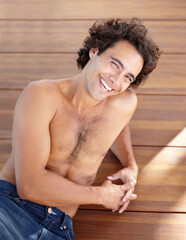 Fototapeta na wymiar Shirtless man, portrait and happpy guy in jeans laying down on wood floor with happy and sexy smile. Attractive, healthy and topless male laughing with relaxing, rest and bare chest in sunshine