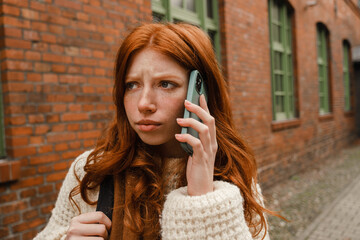 Beautiful girl talking on mobile phone while standing outdoors